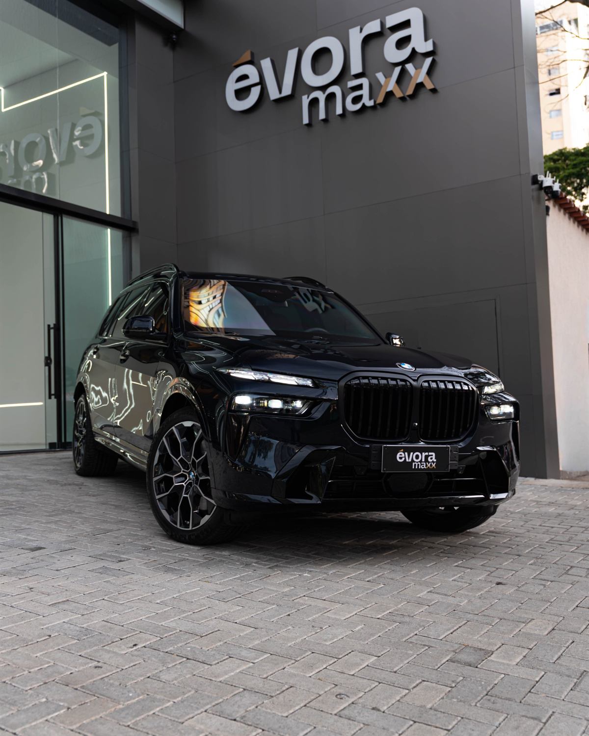 BMW X7 M60i preta em frente à fachada da loja conceito Évora Maxx em Moema